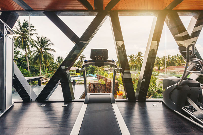 small gym in luxury villa, big window, tropical view with palm trees skyline.